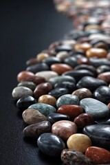 A close up view of a collection of smooth colorful stones on a dark surface in a studio setting