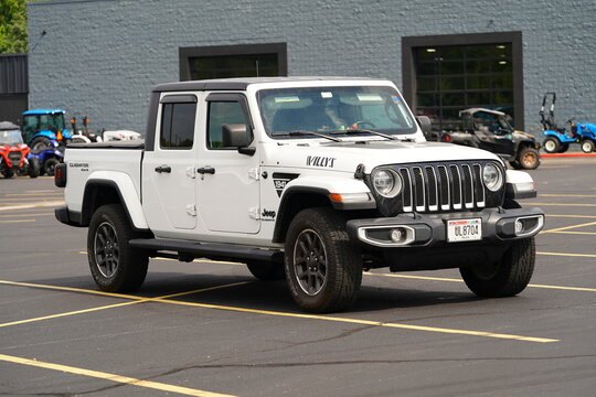 The white 2025 S Gladiator Jeep sits in a parking lot.