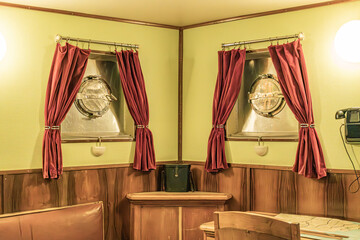Interior of a warship cabin, wooden paneling, red curtains with tiebacks, porthole or round window,...