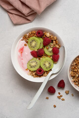 Top View of Raspberry Yogurt in White Bowl with Fresh Kiwi Topping and Ripe Raspberries on Bright Background, Healthy Dessert and Breakfast Concept