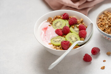 Top View of Raspberry Yogurt in White Bowl with Fresh Kiwi Topping and Ripe Raspberries on Bright Background, Healthy Dessert and Breakfast Concept