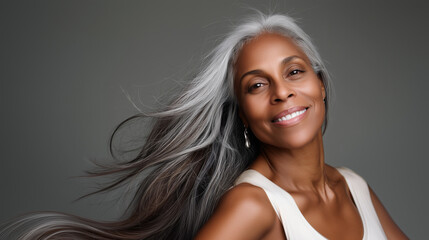 Portrait of a mature black woman with long gray hair flowing in the wind, radiant smile, smooth healthy skin, concept of aging gracefully, natural beauty and skincare advertising b