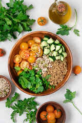 Gluten Free Quinoa Salad with Cucumber, Parsley, Mint and Yellow Cherry Tomatoes in Wooden Bowl on Light Background