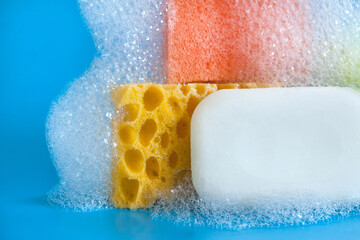 White soap with cleaning sponges and soapy bubbles foam on blue background. 