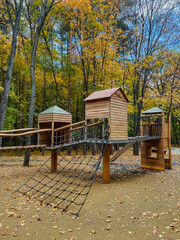 In a park, there is a beautiful wooden playground, complete with slides and swings, surrounded by lush trees that provide shade and enhance the recreational atmosphere of the area