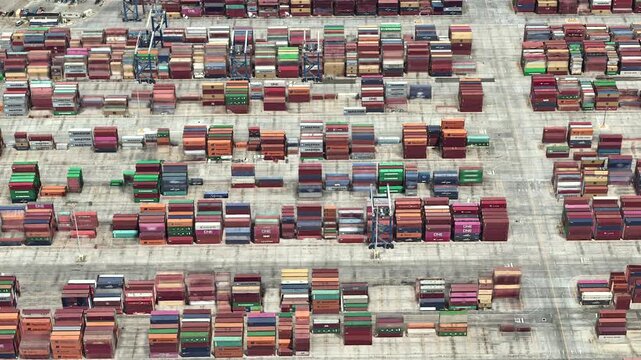 Top View of the Port Warehouse. The camera slowly flies over a huge open-air logistics and warehouse site containing a mass of shipping containers