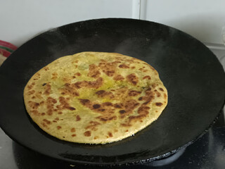 Golden, crispy aloo paratha on tava, stuffed with spiced potatoes and herbs, cooked to perfection with ghee, making a delicious and comforting Indian breakfast or meal.