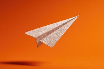 A paper airplane in mid-flight against an orange background.  A minimalist and stylized image