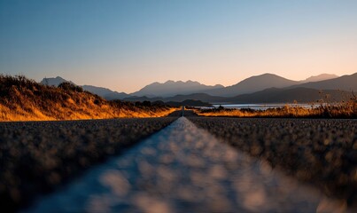 Empty road stretching into a mountain sunset