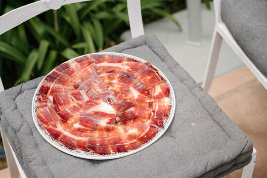 Plato de jam&oacute;n ib&eacute;rico recien cortado sobre una silla
