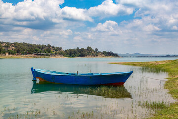 Obraz premium A peaceful lakeshore view. Nature landscape with empty fishing boat standing on the shore.
