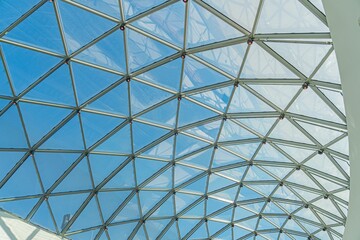 Modern interior space with a glass-paneled, geometric ceiling in an urban setting a