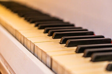 Close-up of a used piano keyboard, soft lighting, black and white keys, subtle reflection, shallow depth of field, angled perspective