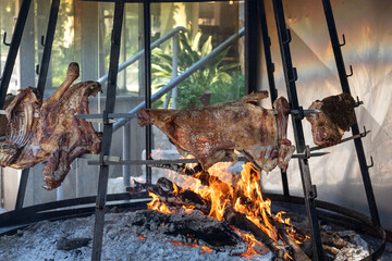 Traditional lamb roasting on an open fire in Crete, Greece. Authentic Greek cooking method with whole meat grilled on metal frames over burning wood and embers. Mediterranean cuisine and cultural food