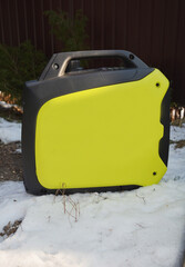 Portable inverter generator stands in the garden in the snow