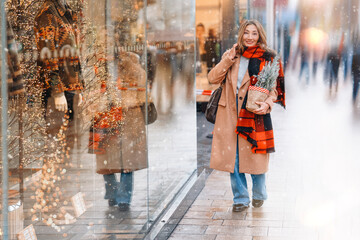 A woman enjoys window shopping during the winter holidays on a snowy city street, admiring the festive displays