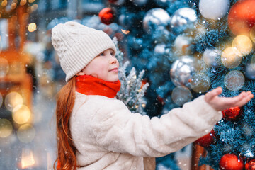 A young girl is delighting in the winter wonderland near a beautifully decorated Christmas tree