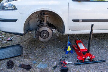 The car is prepared for changing wheels, lifted on a jack and placed next to the car.