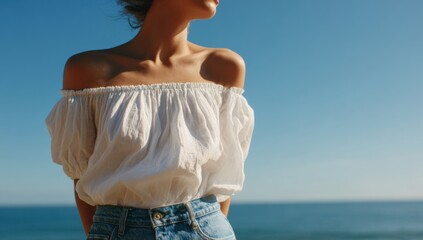 Woman in white top and blue jeans by the ocean