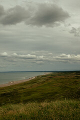 Cloudy shoreline landscape with grassy cliffs and calm sea during afternoon on a coastal area
