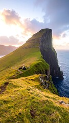 Dramatic sunset over a rugged, grassy mountaintop overlooking the ocean