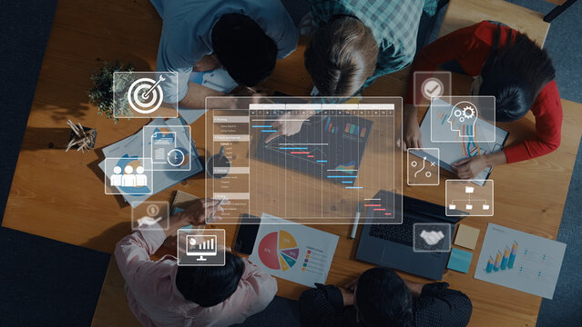 A diverse team collaborates in a modern office, using data visualization tools and analytics on a laptop to enhance their strategic planning and innovation efforts. Trope - Powered by Adobe