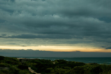 Stormy clouds gather over the ocean at dusk, creating a dramatic and moody landscape