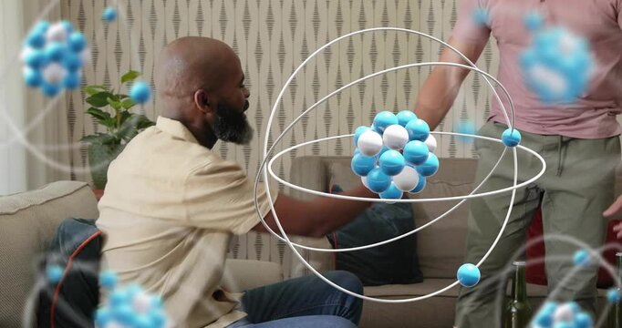 Man focusing on tablet projecting atomic model, friend entering offering drink, discussing science