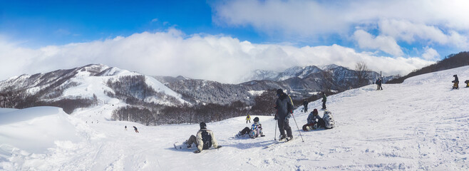 Panoramic winter landscape of a mountain ski resort with people relaxing on a slope (Maiko, Minamiuonuma, Niigata, Japan)