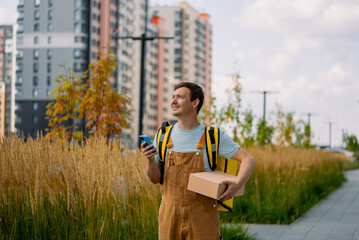 Smiling courier delivering a parcel in a city, using a mobile app for navigation, showcasing modern...