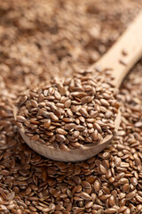 flax seeds in a wooden spoon, a large number of light brown flax seeds and a wooden spoon with seeds, close up