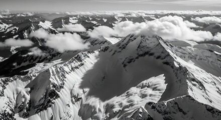 Dramatic monochrome aerial view of snow-capped mountains with cloud cover