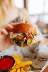 Fresh craft burger with bacon and fresh vegitables, a hand-holding burger in a burger shop