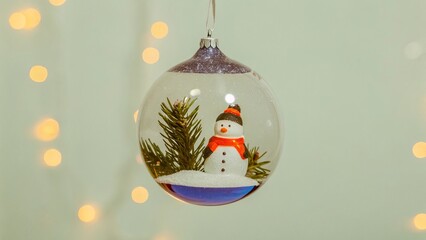 Glass Ornament with Snowman and Pine Branches Against Christmas Tree Lights - 4