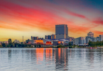 Vibrant Sunset Over City Skyline Reflecting in Tranquil Waters, Minsk, Belarus. Sun sets, colorful...