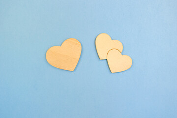 Hearts made of wood on a blue background, a large one and two combined small ones, a concept. Photo with space for copy, concept of family, children and parents, friendship and relationships, hearts