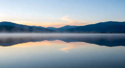 Obraz premium Tranquil Morning Mist Rising Over Serene Lake at Dawn, Majestic Mountains Reflected