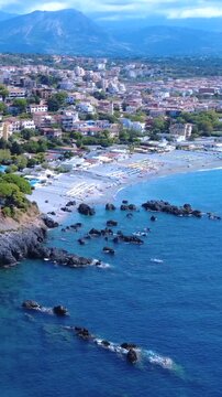 Sunny Beach View With Rocky Coastline and Vibrant Town in the Background on a Clear Day. Scalea, Calabria, Italy.