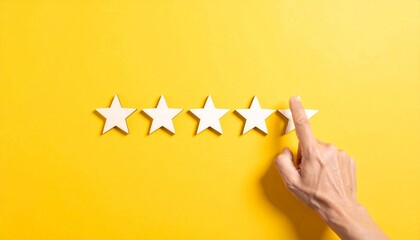 Five wooden stars on yellow background with hand placing the fifth, symbolizing five-star rating and quality recognition.