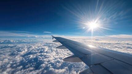 Obraz premium Airplane wing over fluffy clouds, bright sun