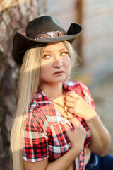 Confident cowgirl adjusting her hat in rustic setting