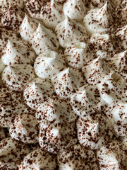 Cream cones or balls sprinkled with coffe. Macro shot, soft focus. Tiramisu cake as textured background. Traditional Italion dessert. Top view.