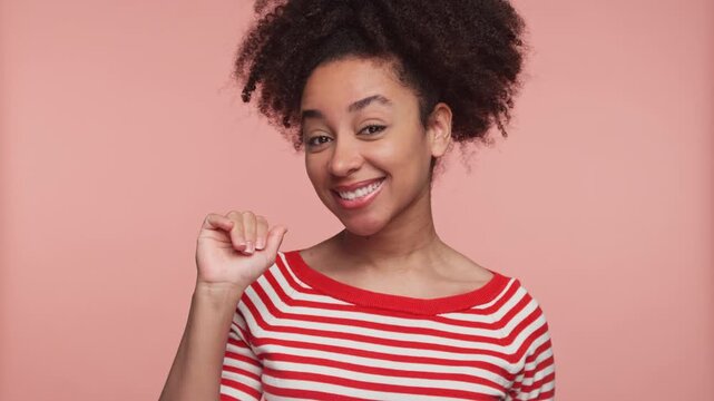 Smiling woman waving hand and saying good bye on pink