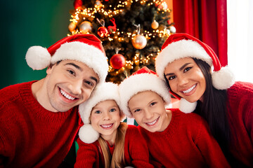 Smiling family celebrating Christmas together at home with festive decorations, wearing matching...