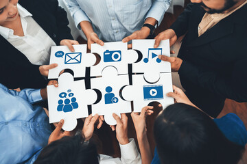 A diverse group holding puzzle pieces with multimedia icons, illustrating teamwork in communication strategies. Perfect for concepts of collaboration and innovation. Amity
