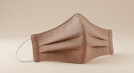 Brown cotton face mask with elastic ear loops resting on a beige surface, showcasing simple design and personal protection.