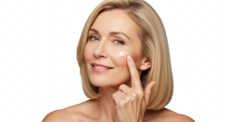 An older woman with blonde hair smiles as she applies cream to her cheek with her finger, isolated on transparent background