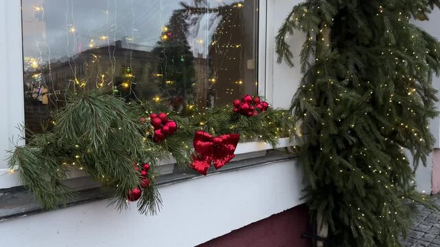 Festive Christmas street decoration featuring vibrant red ornaments, lush greenery, and twinkling lights creating a warm holiday atmosphere with copy space for text