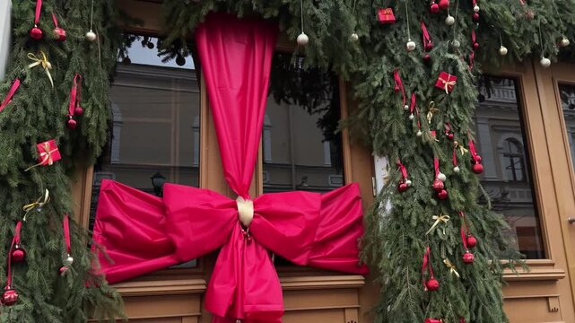 Festive street decoration featuring lush evergreen garlands adorned with vibrant red bows and ornaments, creating a joyful holiday atmosphere for New Year celebrations