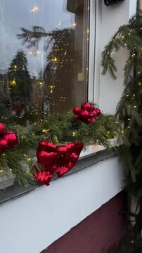 Festive street decorations featuring lush green garlands adorned with red ornaments and twinkling lights, creating a warm holiday atmosphere for New Year celebrations